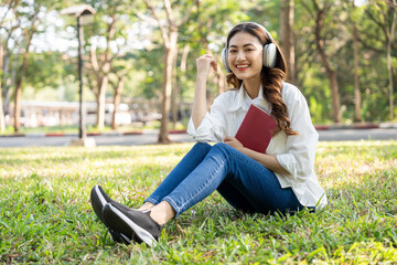 Young asian woman relaxing reading book sitting at public park life style outdoor. Happy female Take a break enjoy time living in the nature. Human and nature together