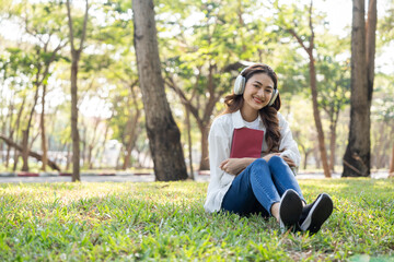 Fototapeta premium Young asian woman relaxing reading book sitting at public park life style outdoor. Happy female Take a break enjoy time living in the nature. Human and nature together
