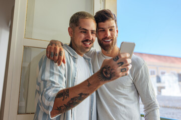 Happy gay couple using smart phone at home