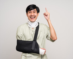 Happy young asian man broken arm on isolated background. Asian man put on plaster bandage cast...