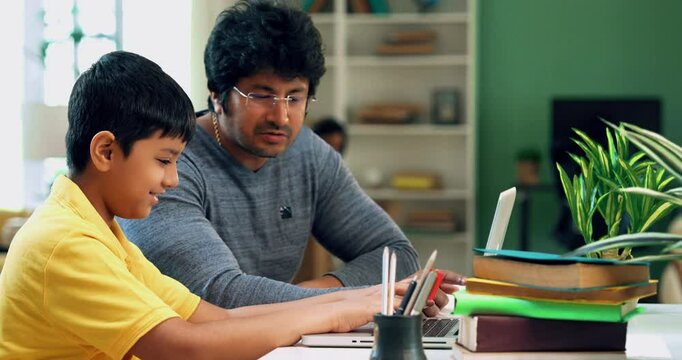 Indian Asian school kid using a laptop for studies while father sits beside, guiding, helping with homework in a modern lavish home, fostering online education, digital learning, and academic success