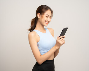 Naklejka premium Young beautiful asian woman with sportswear using smartphone on isolated white background. Attractive Portrait latin sporty woman standing pose holding cell phone exercise workout in studio.