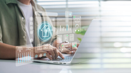 IoT Smart Home Automation and Power Efficiency Control System. Person managing smart home devices through laptop with IoT dashboard showing energy usage, climate control, and connected appliances.