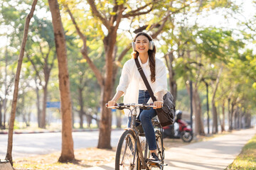 Fototapeta premium Young Asian woman riding bike in nature public park. Sustainable save energy lifestyle. Commute and carbon neutral transportation. Asian woman cycling bike on the nature road.