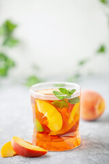 Fruit iced tea with peaches and apples in a glass on the table. Summer drink concept
