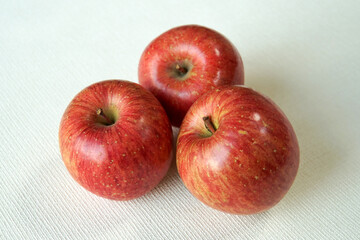 白背景に置かれた食卓を彩る３つの赤リンゴ