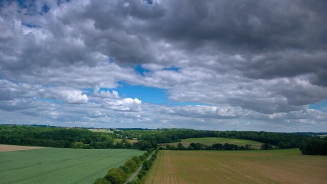 hyper lapse de nuages d'&eacute;t&eacute; passant au dessus d'un champs travers&eacute; par une route de campagne