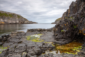 Fototapeta premium The dramatic rocky and slippery shoreline near Smoo cave with the horizon in the background.