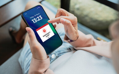 Emergency alert warning displayed on smartphone screen as symbols telling people to be careful. Technology concept
