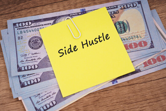 Side hustle concept displayed on a yellow sticky note over currency banknotes and a notebook, representing extra income, freelance work, entrepreneurship, personal finance, and alternative earning opp