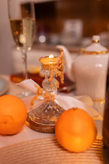 A burnt-out candle in a vintage candlestick stands among tangerines on a festive New Year's table