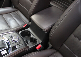 Obraz premium Two round cup holders near the armrest between the seats with expensive leather trim. Comfort and convenience for long travel in a premium car 
