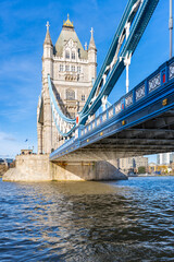 Obraz premium The iconic Tower Bridge in London showcases its architectural beauty under a clear blue sky. The bridge spans the River Thames, reflecting its historic significance and stunning design.