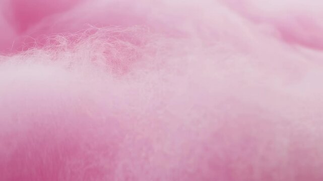 Close-up view of fluffy pink cotton candy with a soft texture and subtle sparkles, evoking a playful and nostalgic atmosphere