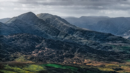 Under a dramatic sky, the Carrauntoohil Walkway offers stunning views of the hills and lush green fields of Ireland.