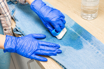 man cleaning jeans from dirt with a brush. woman removing dirty stain on jeans, close-up. dirty...