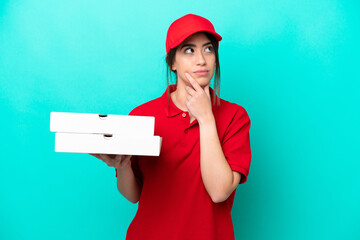 Pizza delivery woman with work uniform picking up pizza boxes isolated on blue background having...