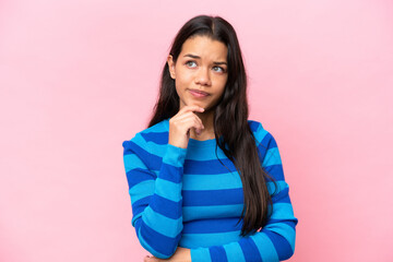 Fototapeta premium Young Colombian woman isolated on pink background having doubts and thinking