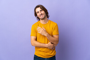 Young handsome man isolated on purple background laughing
