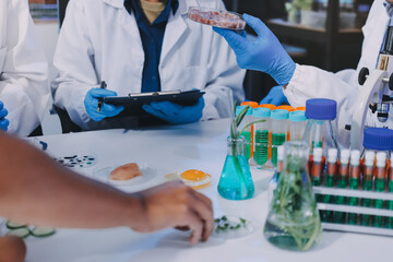 Team Asian scientists in a lab conducting food research using a microscope and lab equipment,...
