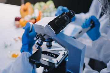 Team Asian scientists in a lab conducting food research using a microscope and lab equipment,...