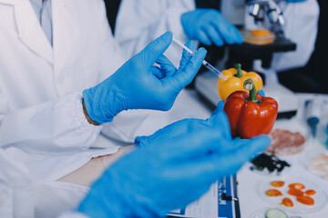 Team Asian scientists in a lab conducting food research using a microscope and lab equipment,...