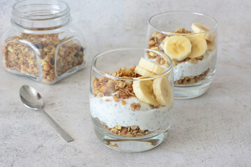 Healthy Yogurt Parfait with Granola and Bananas in drinking glass close up
