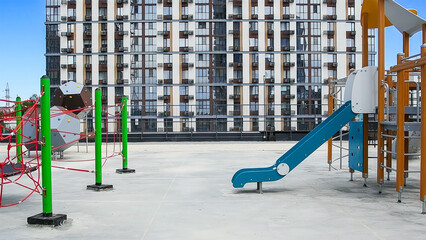 Playground with slides and swings on the background of an apartment building
