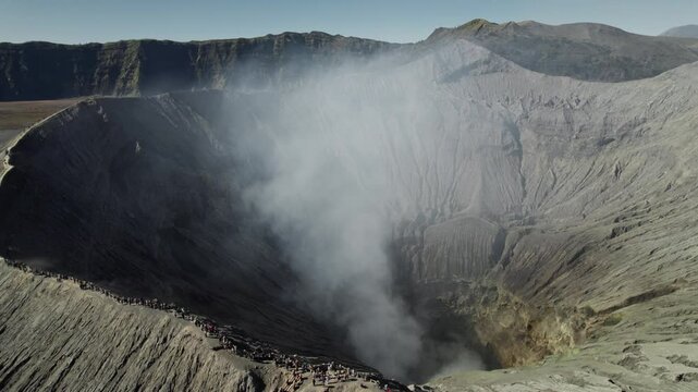 Mount bromo crater emitting smoke and tourists watching
