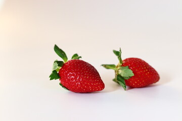 Two ripe strawberries with vibrant red color and fresh green leaves