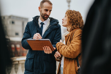Professional individuals collaborate and review business data using a tablet during an outdoor...