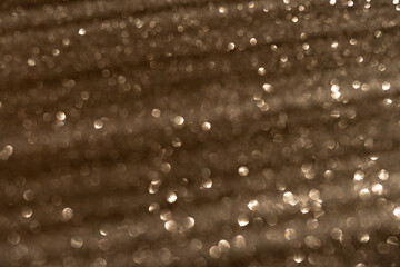 Blurred photo glitter texture on black background.