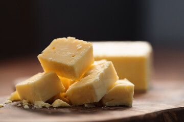 White cheddar cheese pieces on olive wood board