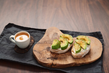 Avocado sandwiches with espresso for breakfast on walnut wood table