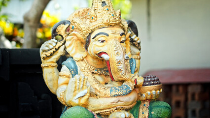 An old hindu stone statue of Ganesha covered with moss, standing on the street on the Bali