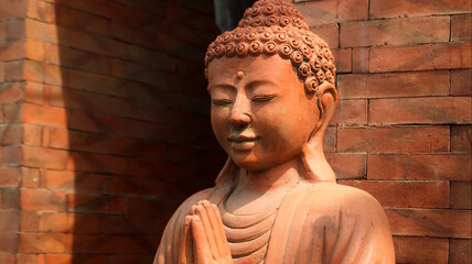 An old red clay statue of Buddha standing on the street on the bali