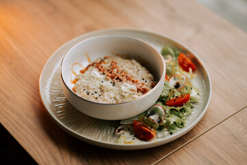 Savory oatmeal topped with crispy bacon and parmesan served with fresh salad