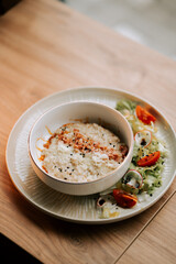 Savory oatmeal topped with bacon and parmesan served alongside fresh salad