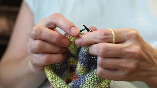 Closeup woman hands knitting wool scarf. Shallow focus.