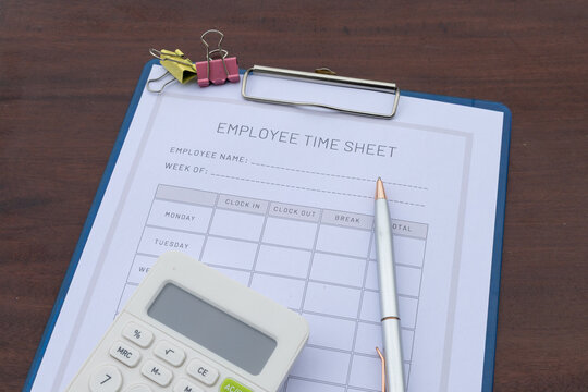 A work shift tracking document is placed in a clipboard on an office desk, symbolizing human resource and payroll documentation.