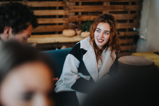 Red-haired woman in a festive social setting engaging in lively conversation with others.