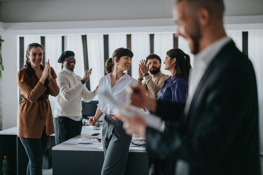 A motivated group of professionals engaging in teamwork during a joyful business meeting, expressing teamwork and celebration.