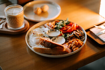 Breakfast spread featuring eggs, greens, and bread on a wooden table in a cozy cafe