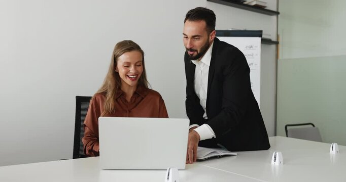 Smiling multiethnic team members engaged in collaborative, productive workflow using laptop, review project data, brainstorm solutions, analyze performance metrics feel satisfied with teamwork results