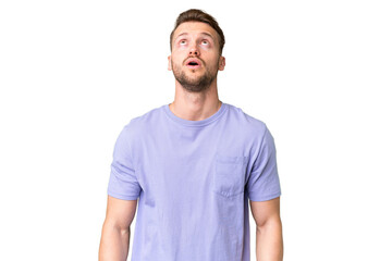 Young handsome caucasian man over isolated chroma key background looking up and with surprised...