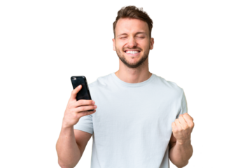 Young handsome caucasian man over isolated chroma key background using mobile phone and doing victory gesture