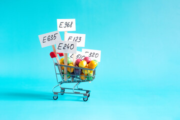 A grocery cart with various colored food additives and information signs in close-up on a light background © Лозовая Людмила