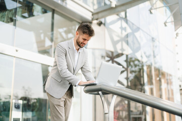 Fototapeta premium Successful businessman works outdoors near the office holds a tablet
