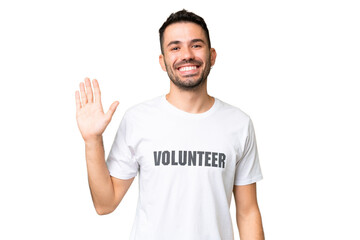 Naklejka premium Young volunteer caucasian man over isolated chroma key background saluting with hand with happy expression