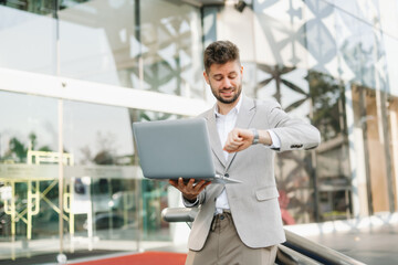 Fototapeta premium Successful businessman works outdoors near the office holds a tablet